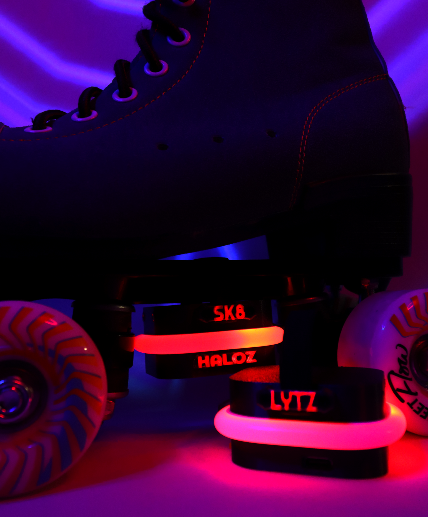 Black roller skates with glowing neogleamz SK8Lytz HALOZ Roller Skate Lights on a dark background